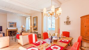 Comedor con mesa de madera dispuesta para cuatro personas, sillas rojas y una araña.