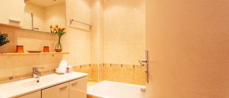 A modern bathroom with a bathtub, a sink, and a mirror.