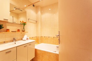 Une salle de bain moderne avec une baignoire, un lavabo et un miroir.