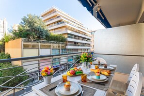 Un balcon avec une table mise pour le petit-déjeuner, comprenant des assiettes, des tasses et un vase rempli de fleurs.