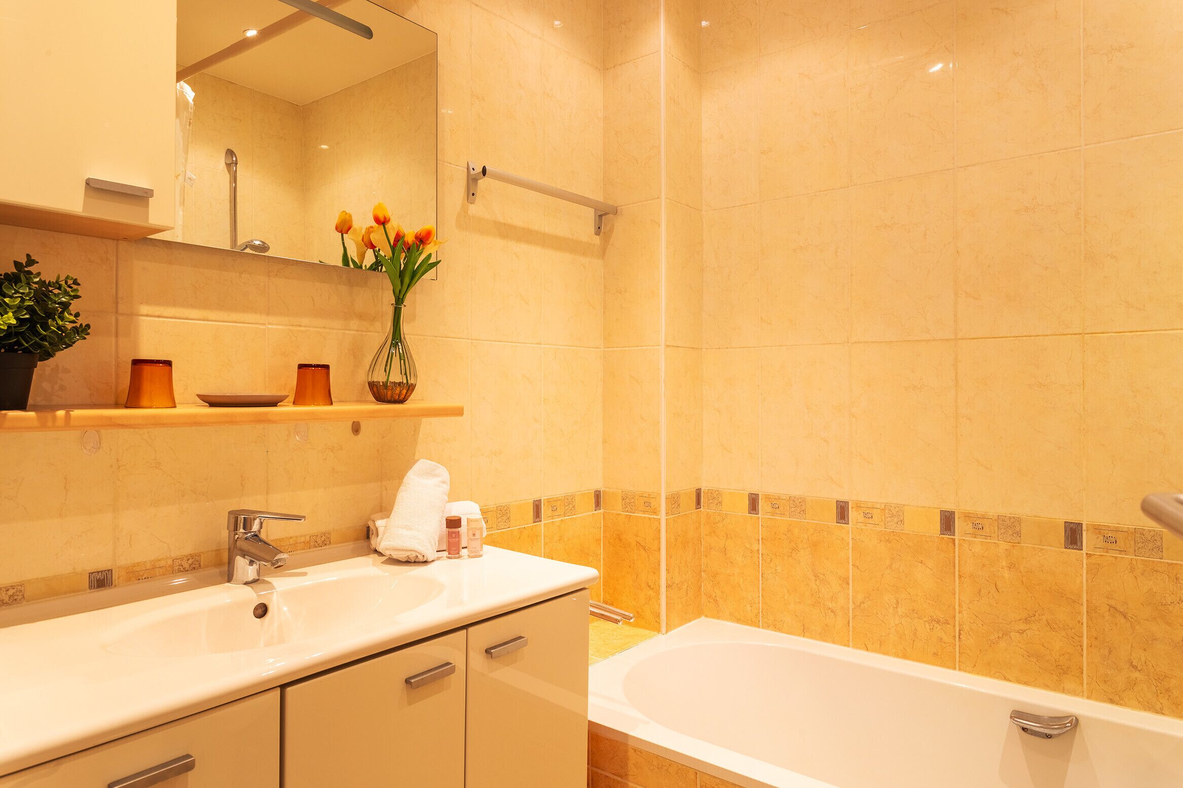 A bathroom with a sink, mirror, and bathtub.