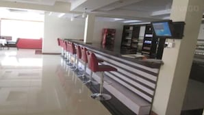 Un espace vaste doté d’un long comptoir et de plusieurs tabourets de bar rouges.