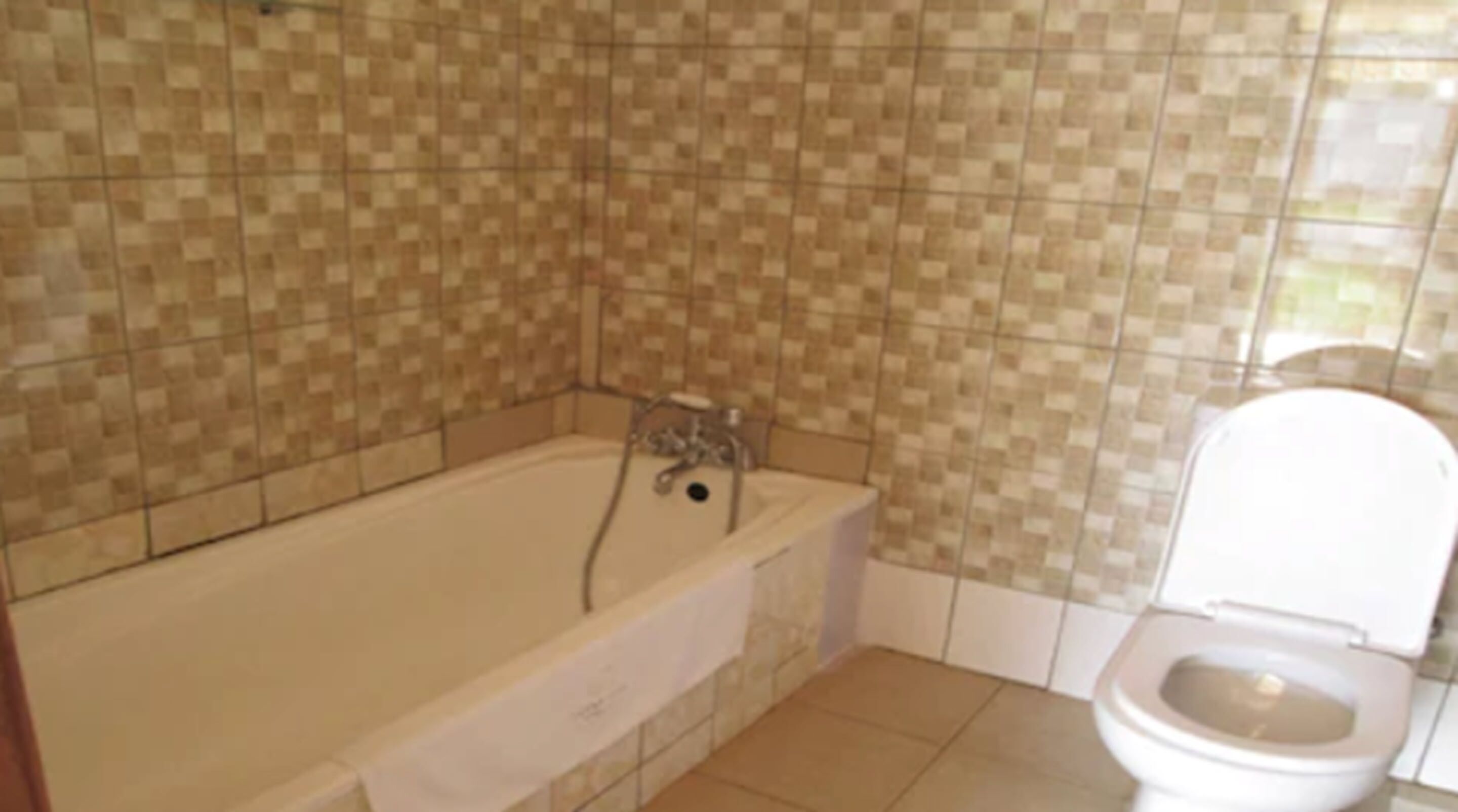 A bathroom with a bathtub, toilet, and tiled walls.