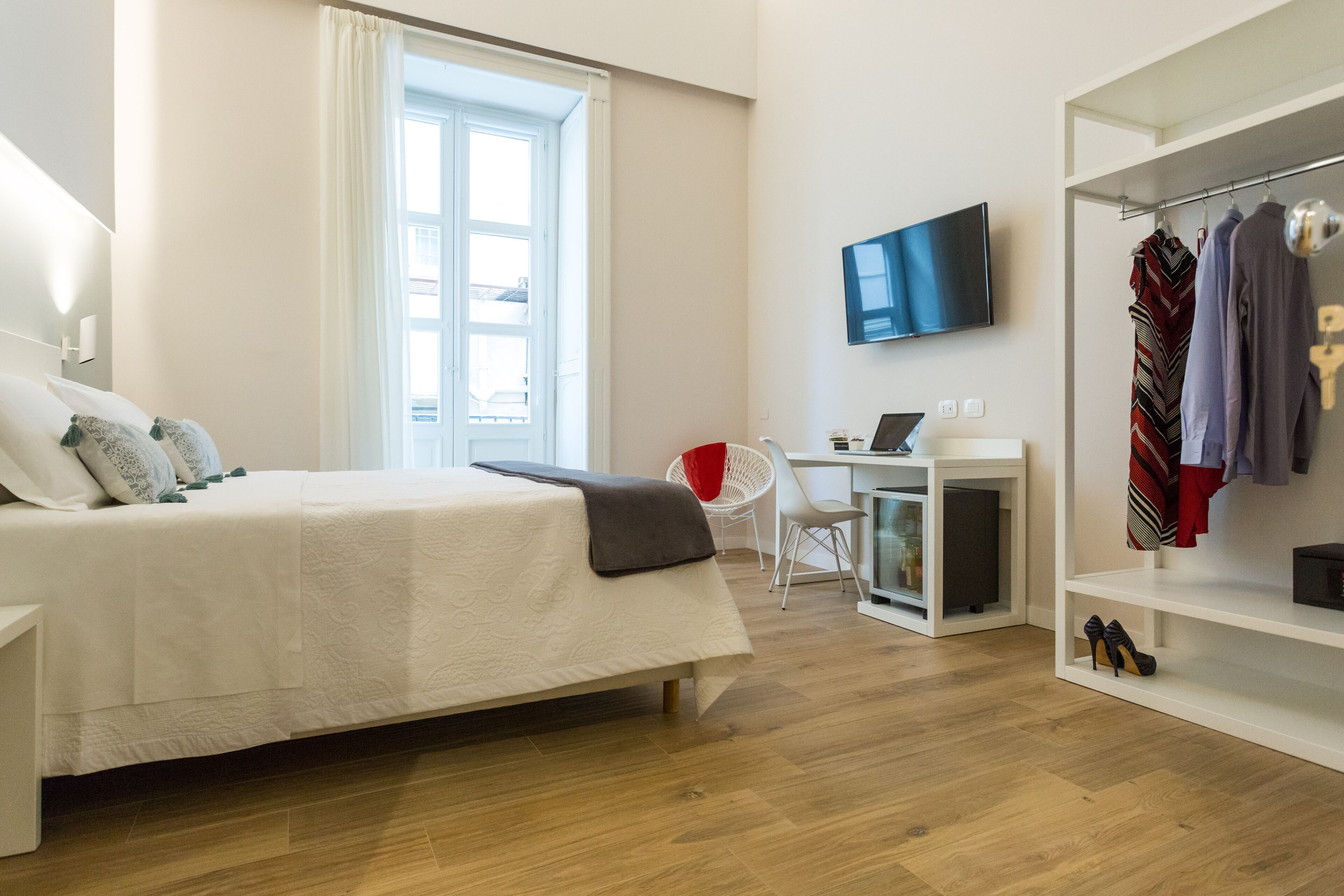 A modern hotel room with a bed, a desk, a TV, and a wardrobe.