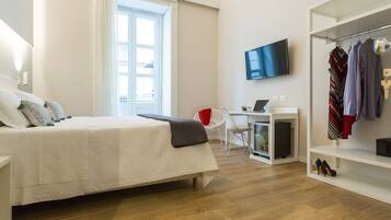 A modern hotel room with a bed, a desk, a TV, and a wardrobe.