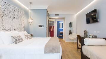 A modern hotel room with a large bed, a desk, a chair, and a TV mounted on the wall.