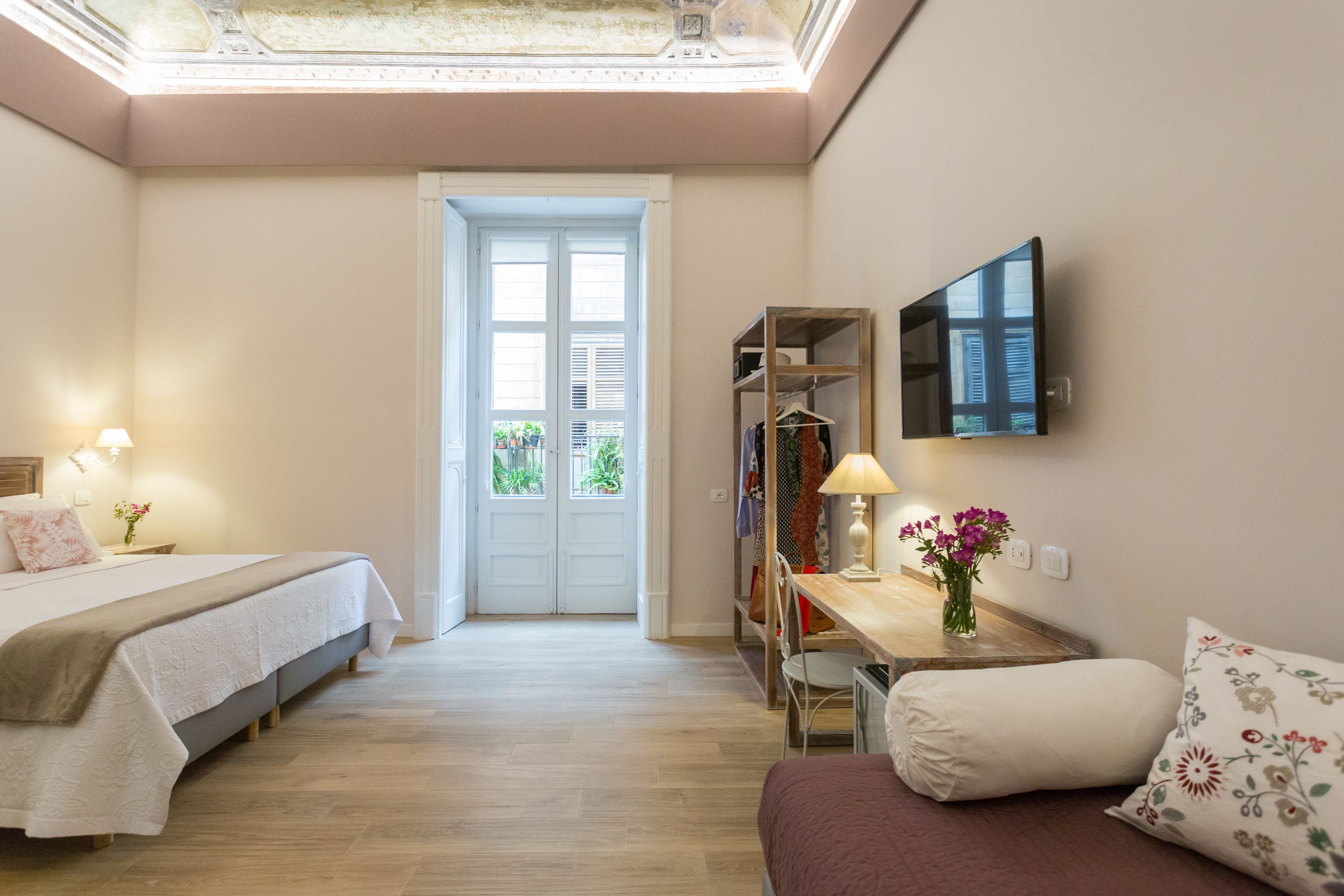 A bedroom with a bed, bedside table, lamp, and a small desk with a chair.
