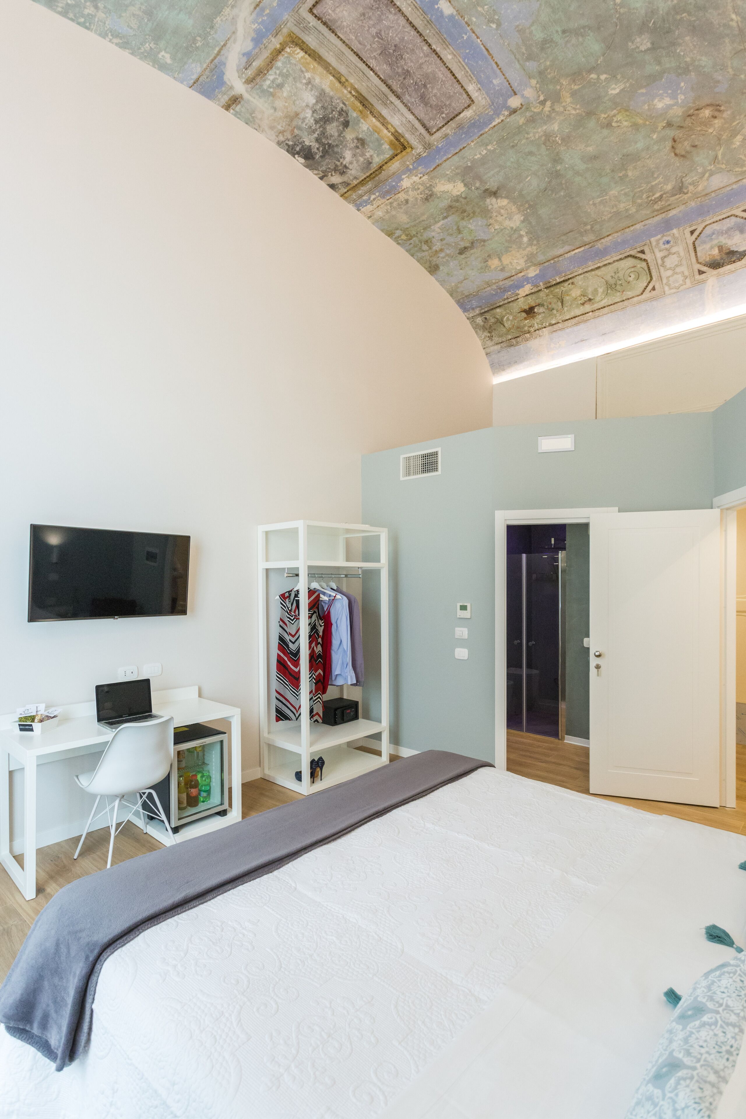 Un dormitorio moderno con una cama grande, un escritorio, un televisor, un armario y un vestidor.