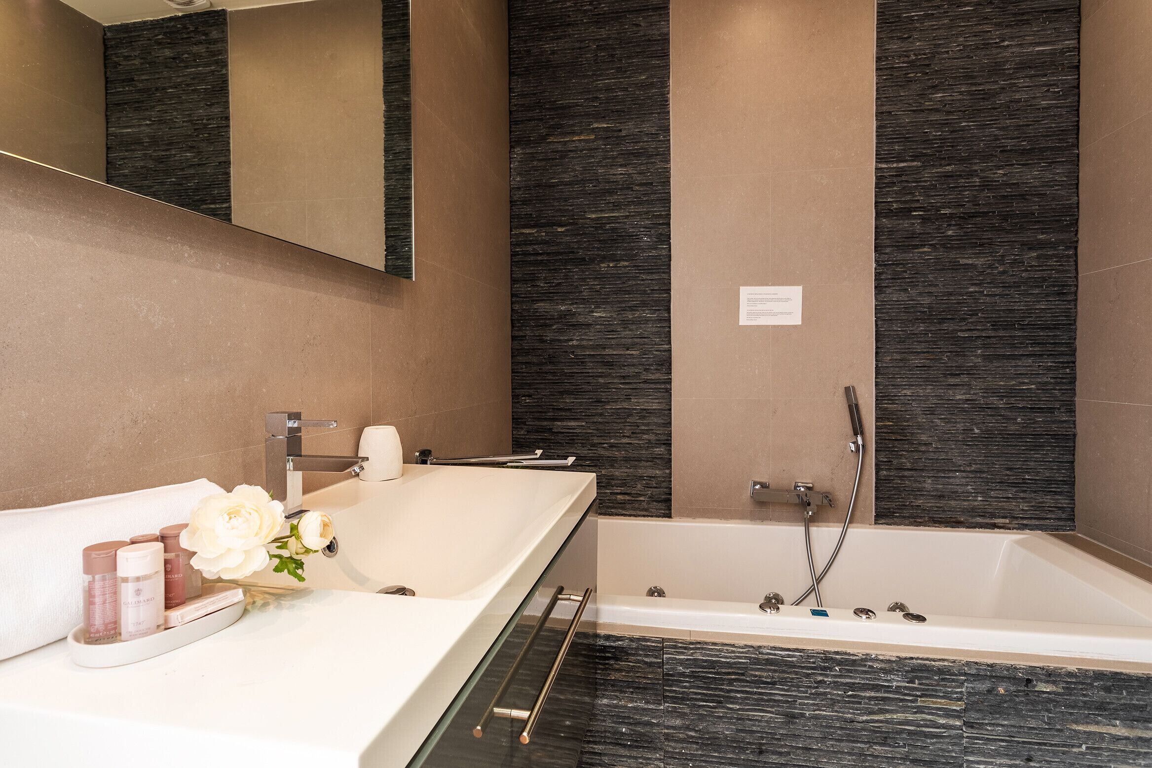 Un baño moderno con una bañera grande, un tocador con espejo y un lavabo.
