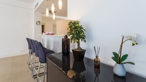Uma sala de jantar moderna com uma mesa preta, cadeiras e plantas em vasos.