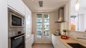 Uma cozinha moderna com forno embutido, exaustor de aço inoxidável e uma janela grande com vista para uma varanda.