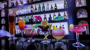 A bar with various cocktails and a shelf of liquor bottles in the background. - Siddhartha Cottage Butwal (Butwal)