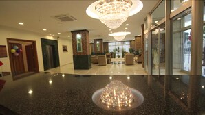 A lobby with a polished marble floor, a large chandelier, seating area, and a reception desk.