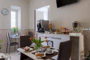 A hotel breakfast area with a coffee machine, a fruit display, and a sign reading "Suite Horti Sallustianni". - Suite Horti Sallustiani (Rome)