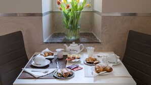 A breakfast table with croissants, pastries, and a vase of tulips. - Suite Horti Sallustiani (Rome)