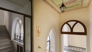 A staircase leading to a balcony with a checkered floor, a wall-mounted light fixture, and a decorative ceiling. - Suite Horti Sallustiani (Rome)
