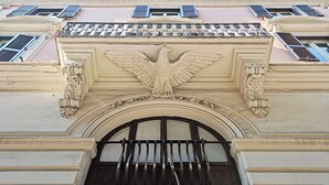 A building facade with a decorative archway and an eagle emblem above it. - Suite Horti Sallustiani (Rome)