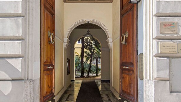 A hallway with a checkered floor leading to an arched doorway. - Suite Horti Sallustiani (Rome)