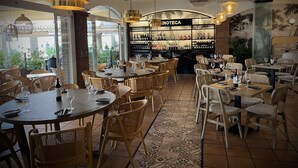 A restaurant interior with round tables, wicker chairs, and hanging pendant lights. - Marissal (Nerja)