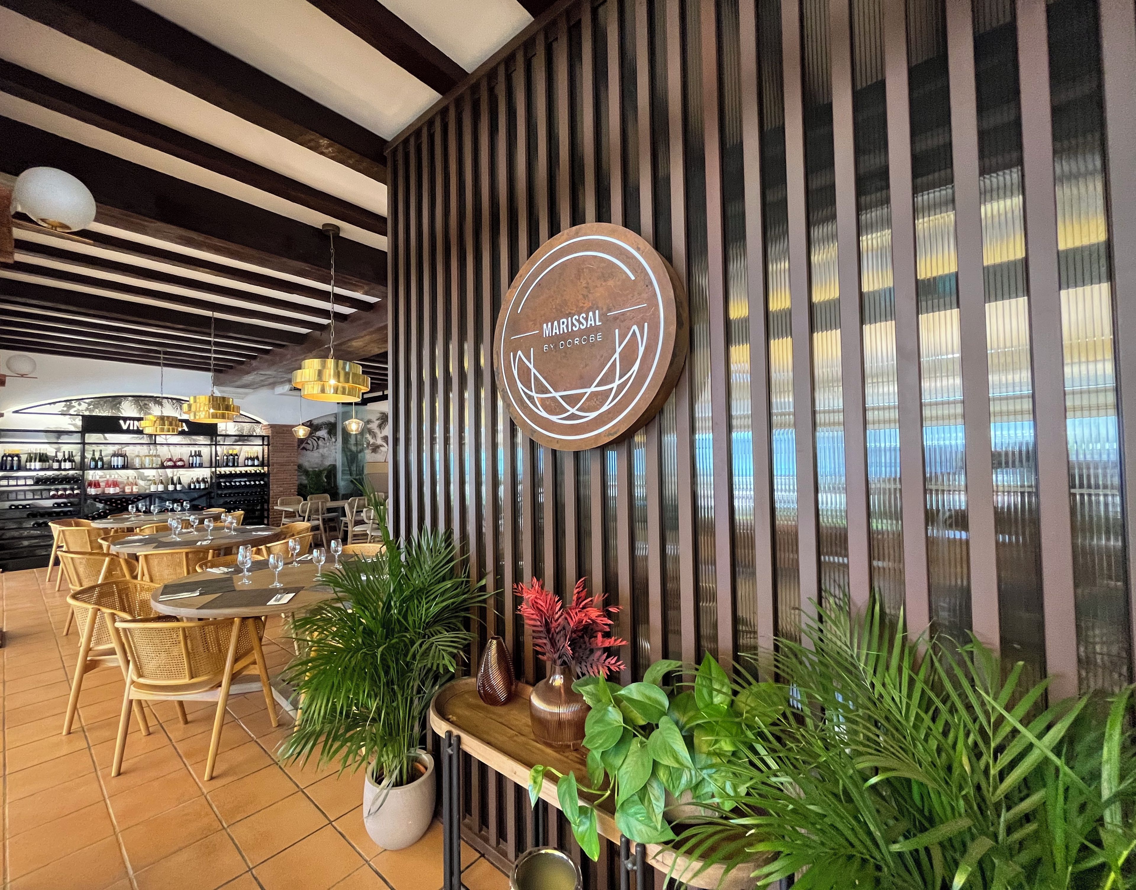 A restaurant interior with a wooden wall, a wine display, and several tables and chairs.