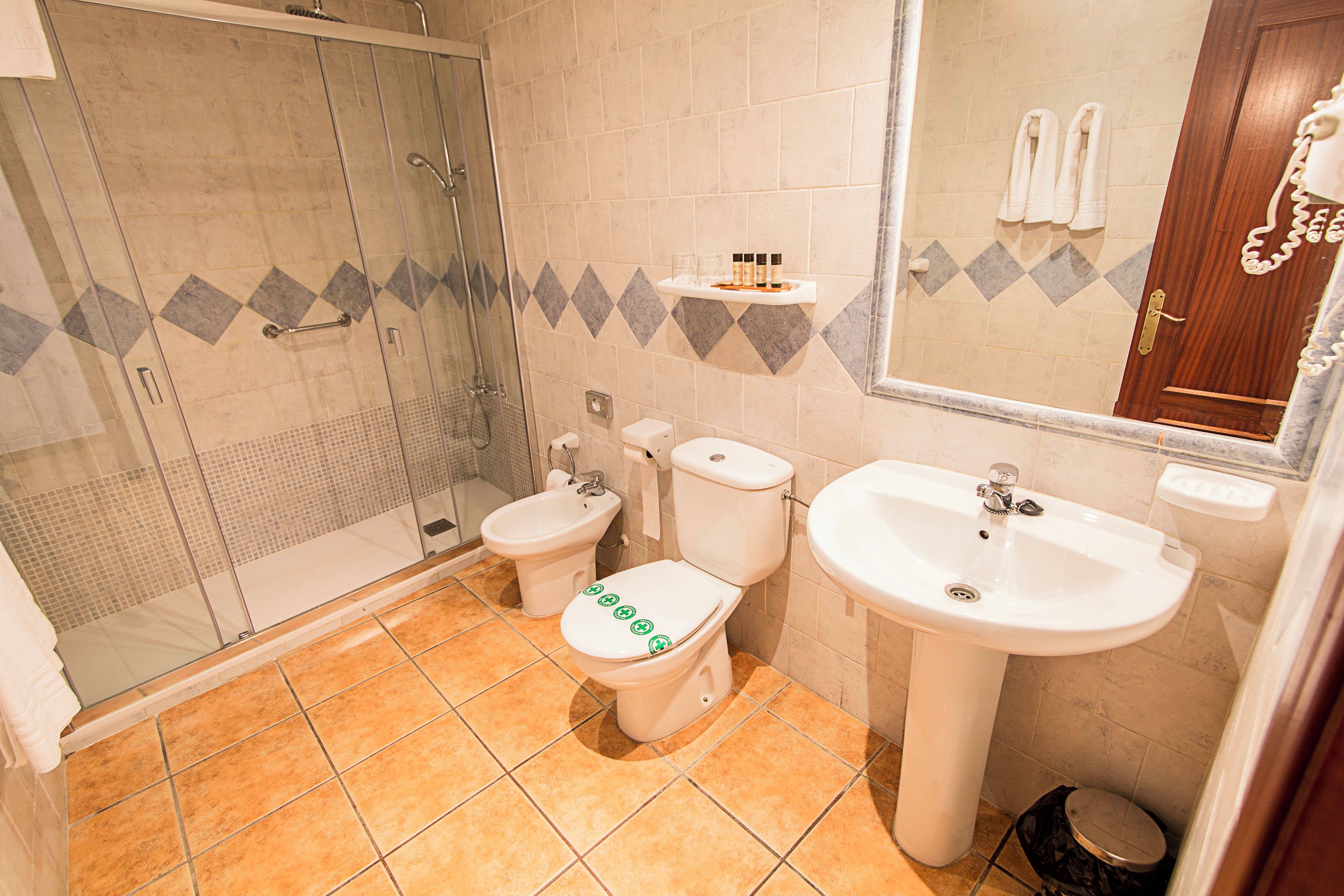Un baño con ducha, inodoro, bidé, lavamanos y espejo.