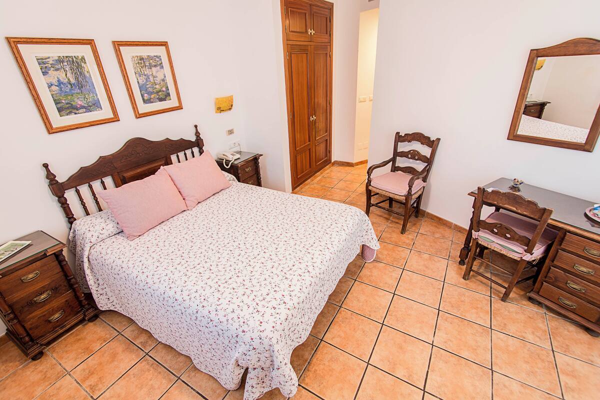 Um quarto com uma cama, uma cadeira, uma cômoda e um guarda-roupa.