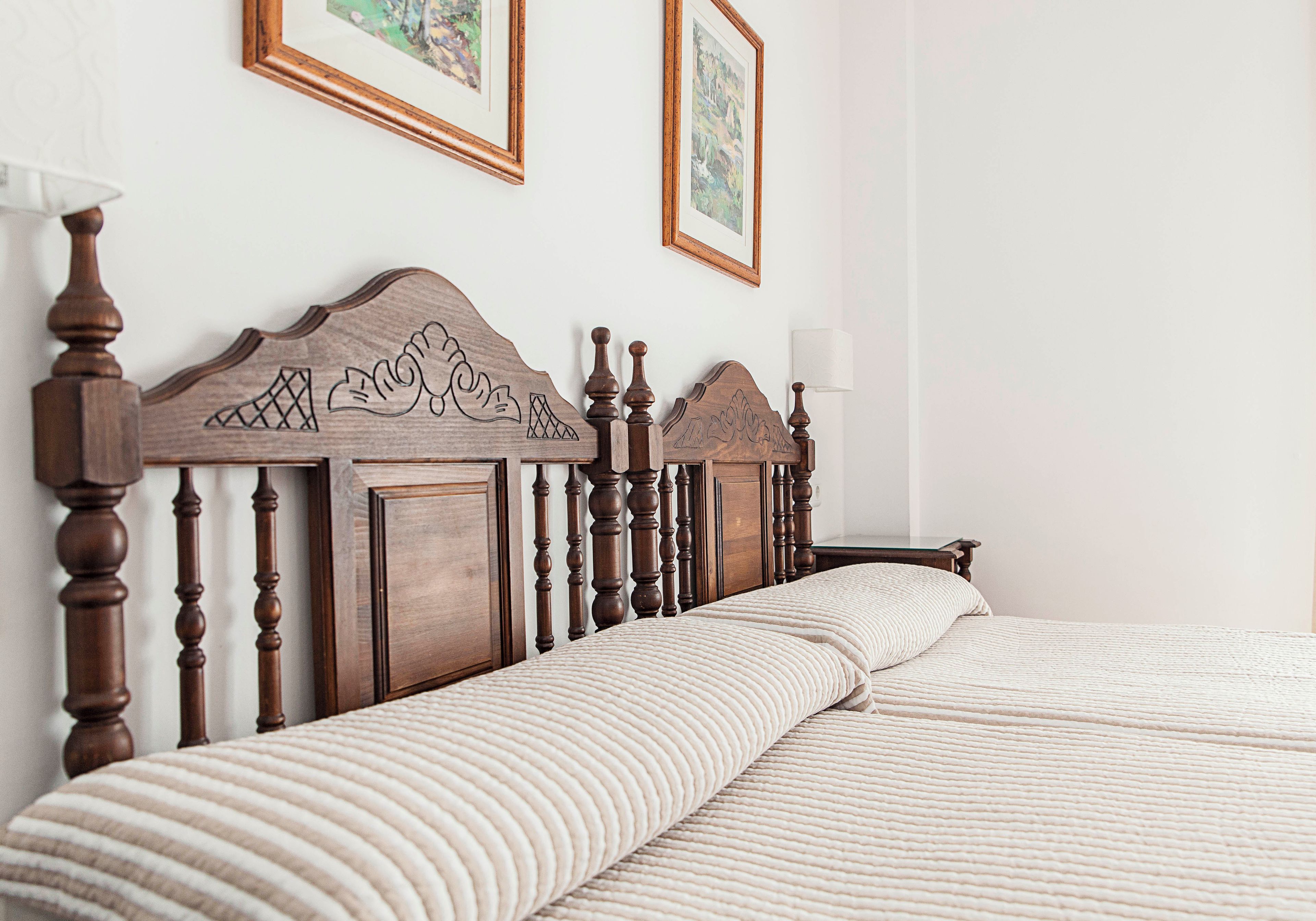Una cama bien tendida con un cabecero de madera y una colcha blanca con textura.