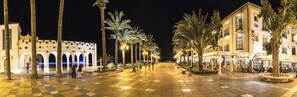 A well-lit square with a central fountain, surrounded by palm trees and buildings with balconies. - Marissal (Nerja)