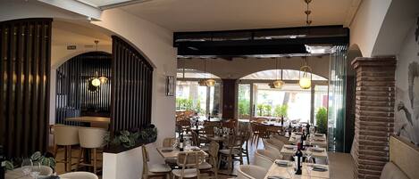 A restaurant interior with high ceilings, exposed beams, and a mix of wooden and upholstered furniture.