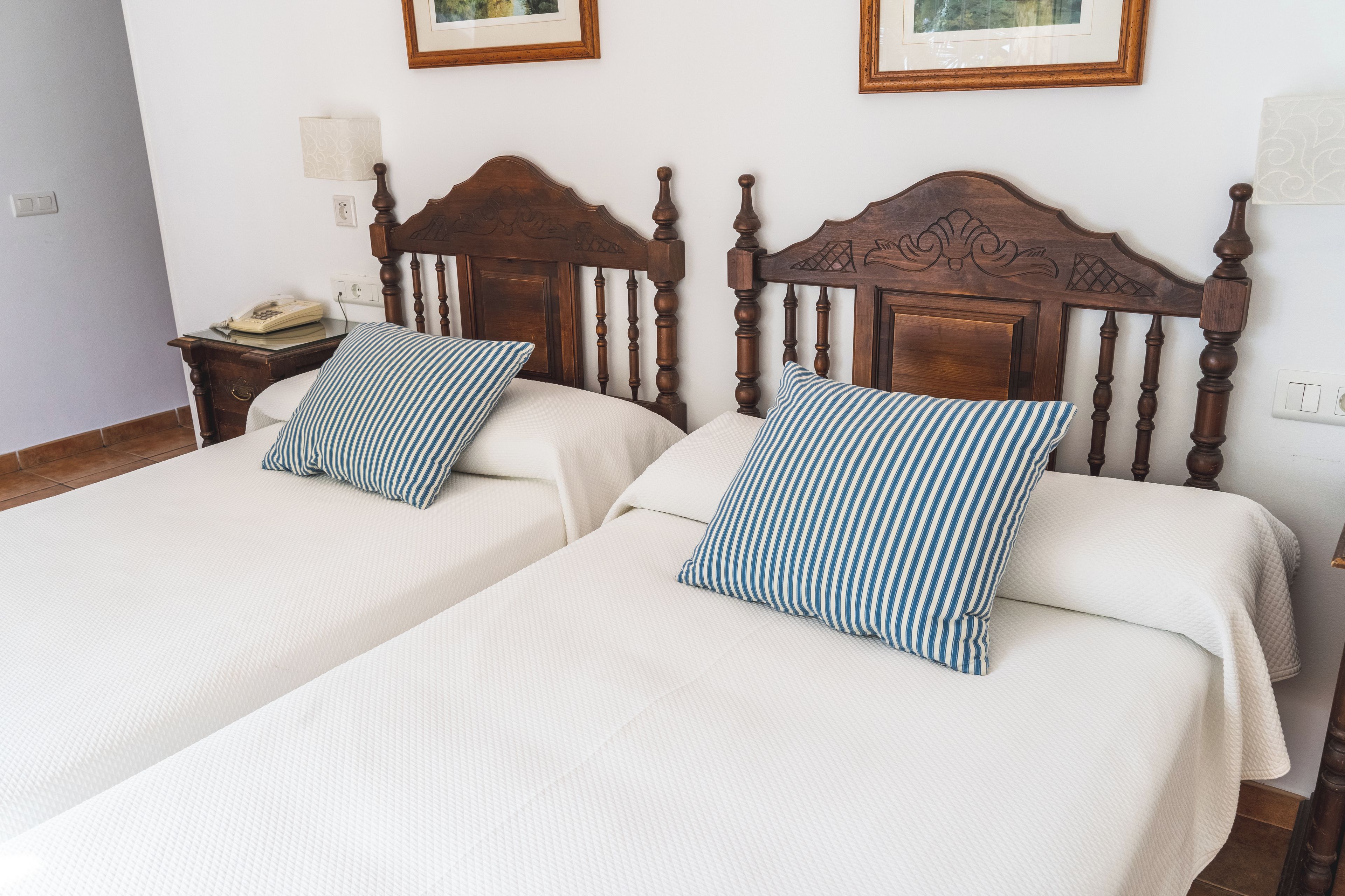 Two single beds with wooden headboards, white bedding, and striped pillows.