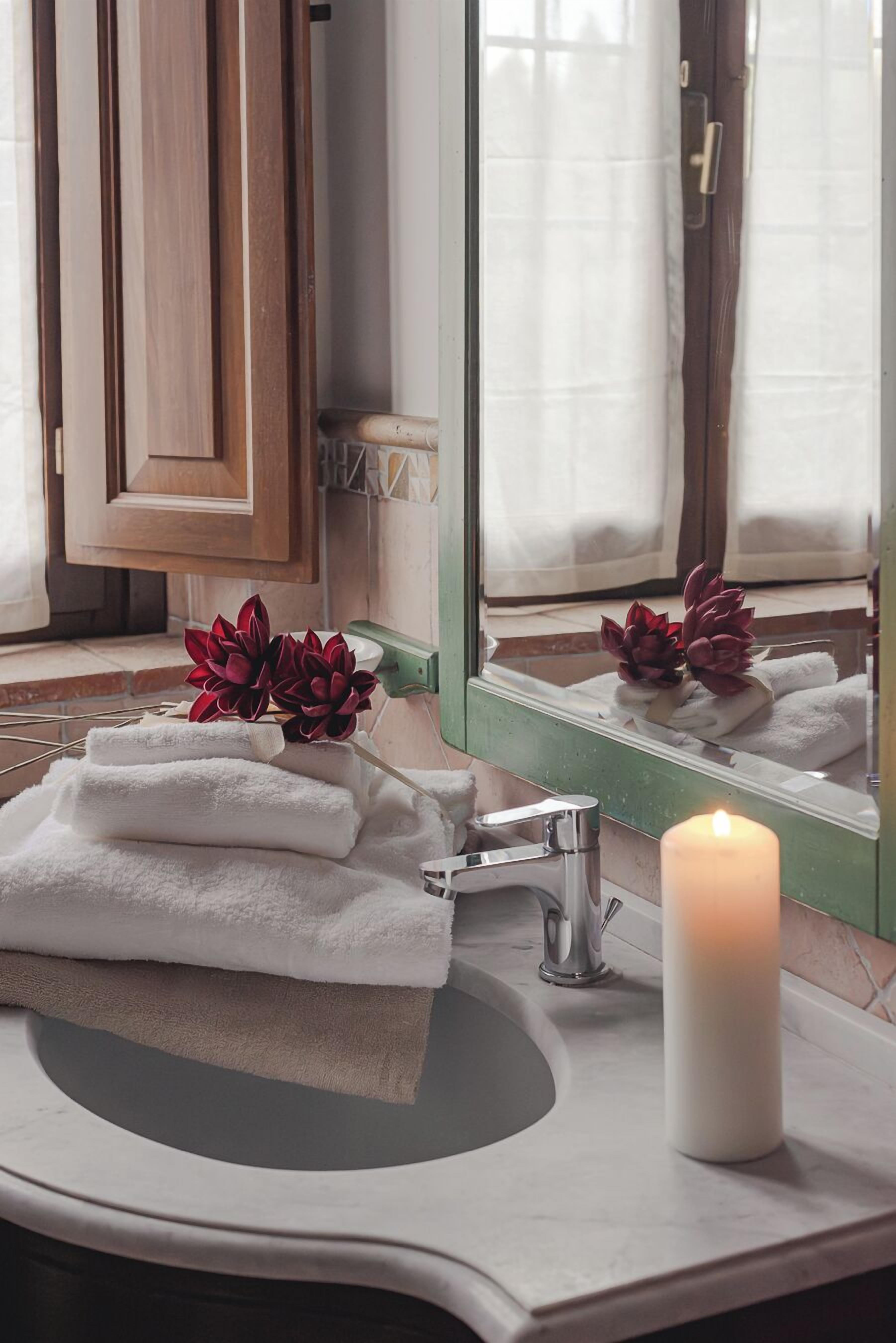 A bathroom with a sink, mirror, and a candle.
