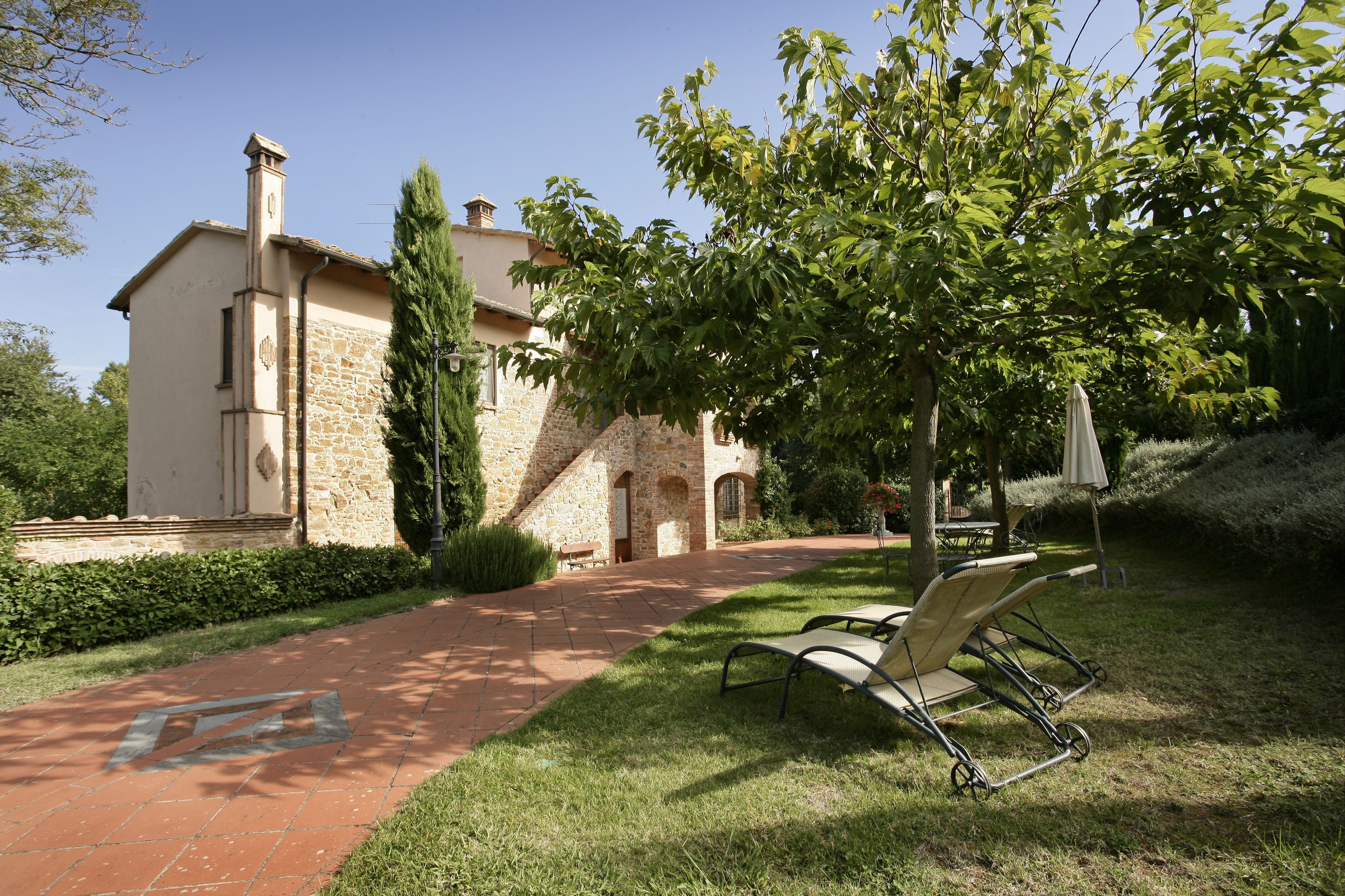 A stone building with a paved pathway leading to a bench.