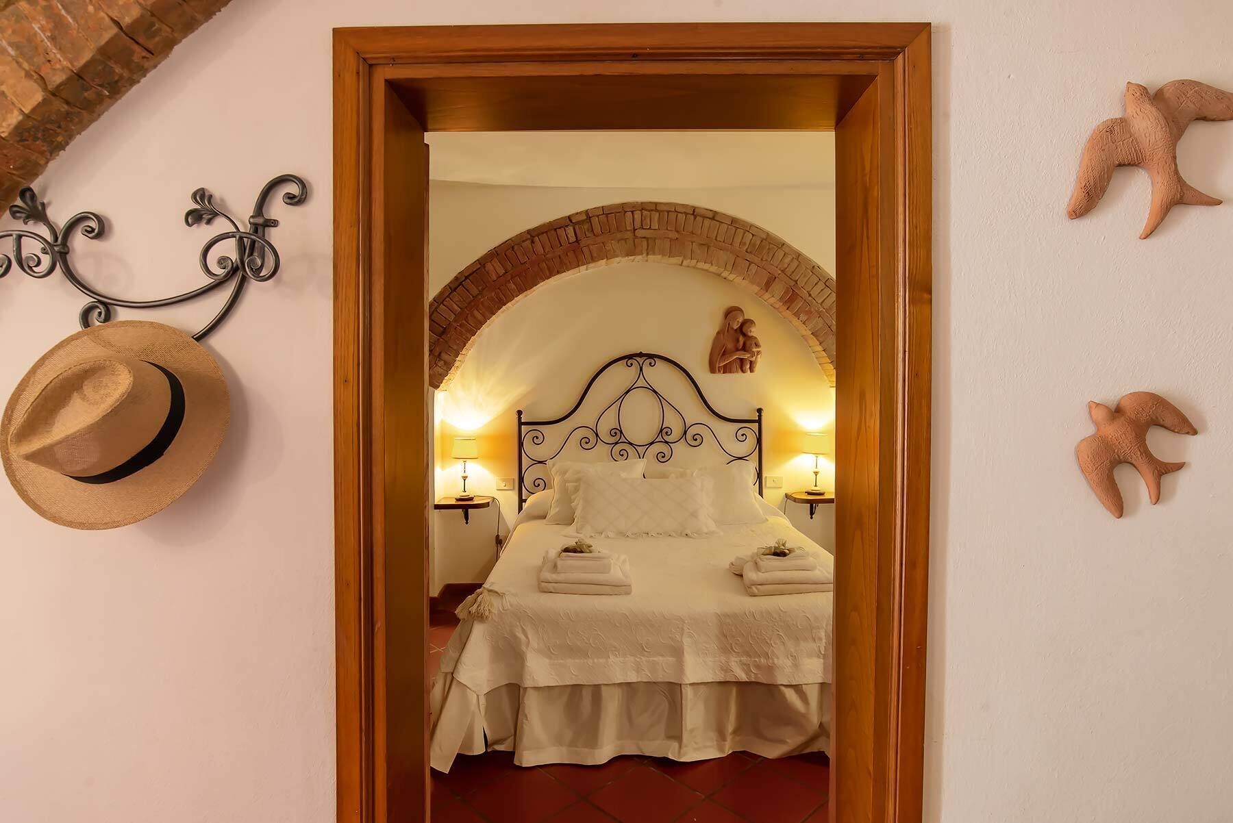 Un dormitorio con cama, cabecero de madera, espejo y un sombrero en la pared.