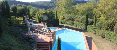 En säsongsöppen utomhuspool, parasoller och solstolar