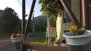 A wooden sign with the name "ROMULUS" and two metal buckets with flowers. - Lodge Romulus (Rusutsu)