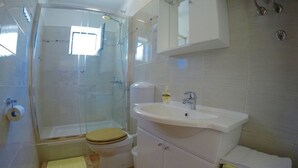 A bathroom with a shower, toilet, sink, and cabinet. - Vila Lacman (Hvar)