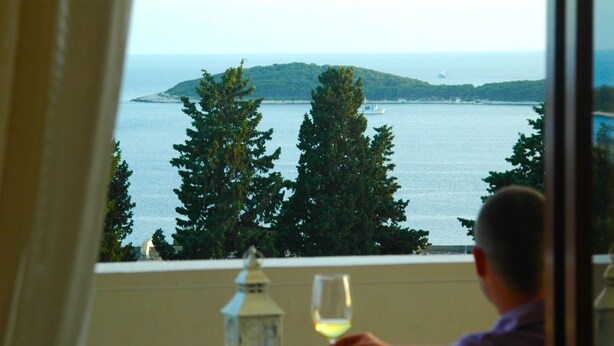 A person seated at a table with a view of the sea and a distant island. - Vila Lacman (Hvar)