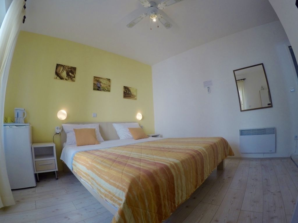 A bedroom with a bed, bedside tables, a ceiling fan, and artwork on the wall.
