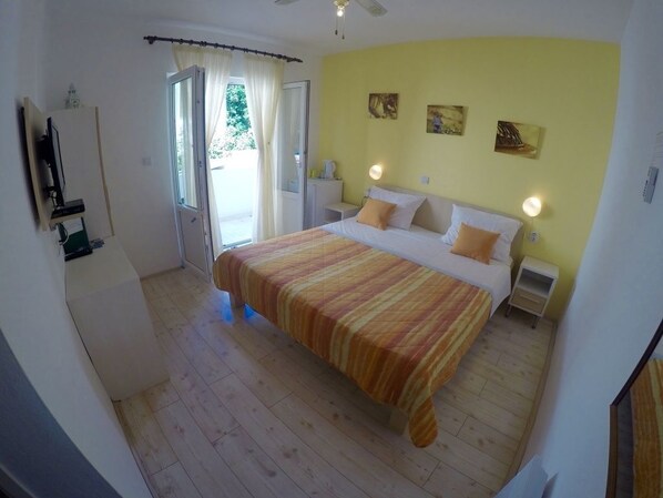 Un dormitorio con cama, mesitas de noche y ventana con cortinas.