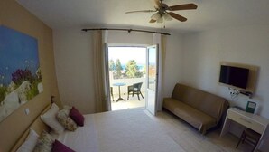 A hotel room with a bed, a desk, a television, and a balcony with a view. - Vila Lacman (Hvar)