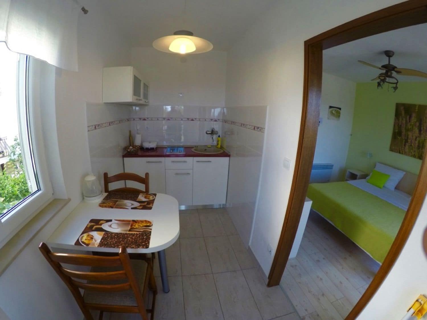 A compact kitchen with white cabinets, a dining table with chairs, and a window.