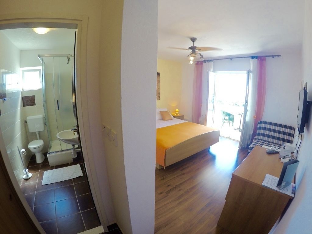 A hotel room with a bathroom, a bed, a desk, and a view of the outside.