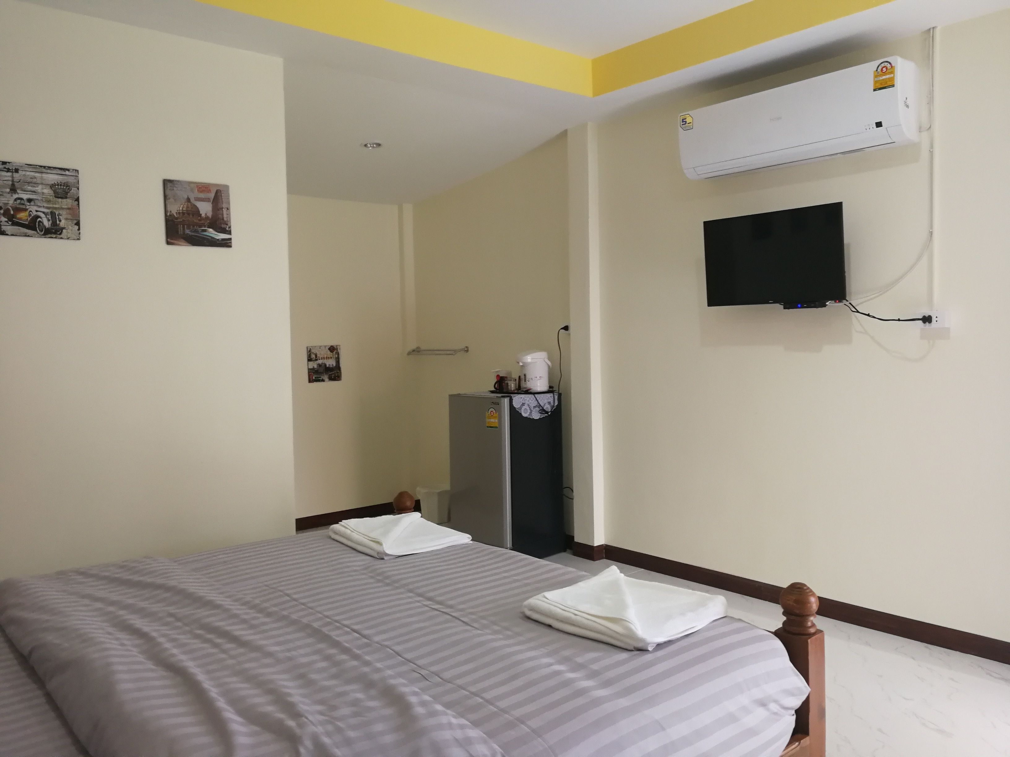 Ein Hotelzimmer mit zwei Betten, einem an der Wand montierten Fernseher und einer Klimaanlage über den Betten.
