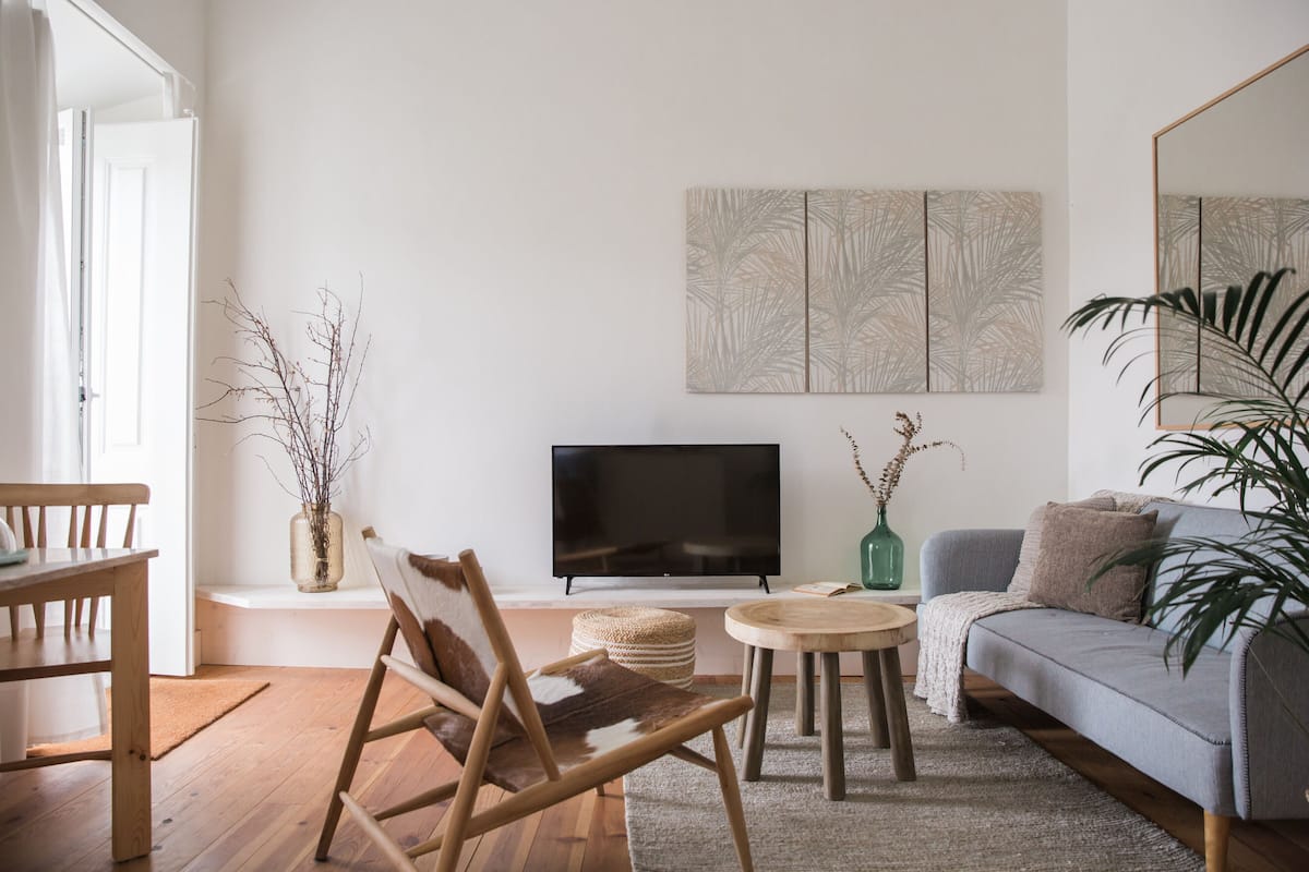 Een woonkamer met houten vloer, een bank, een televisie, een salontafel en een stoel.