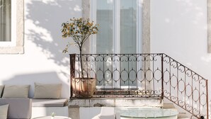 A modern outdoor seating area with a sofa, a small table, and a potted plant.