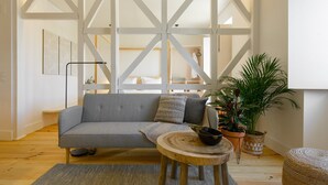 A modern living room with a grey sofa, a round wooden table, and a potted plant.