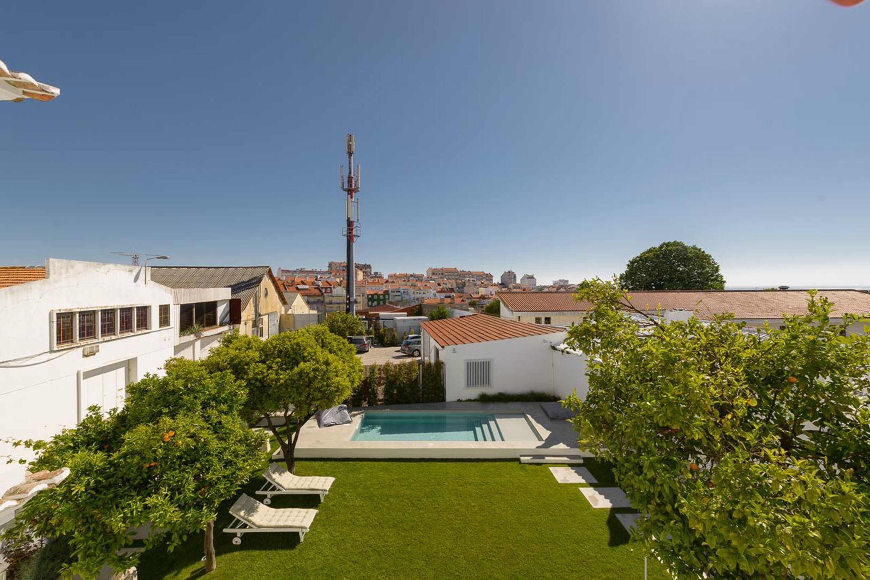 A residential area with a swimming pool, white houses, and a clear view of the cityscape in the background.