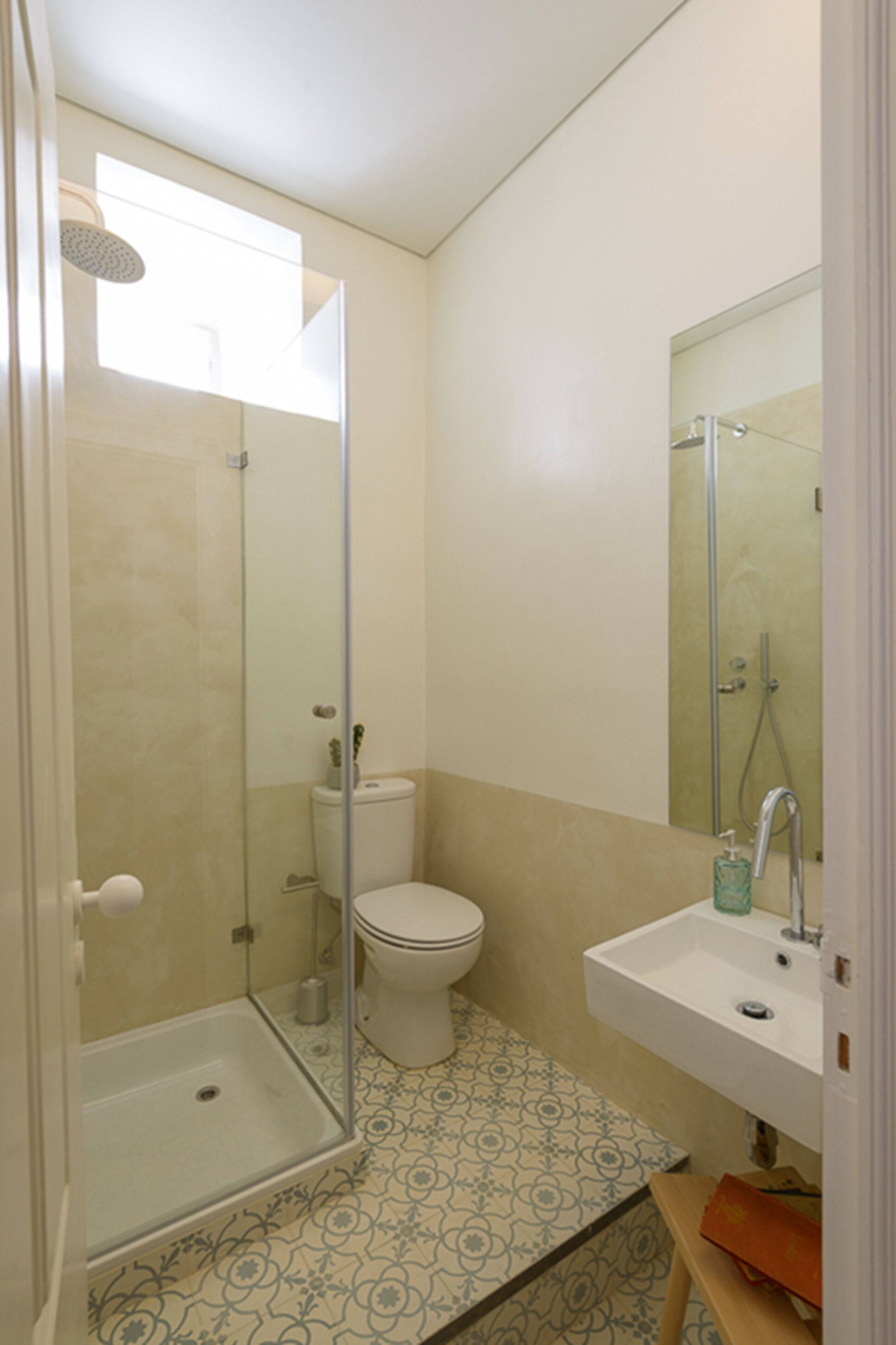 A bathroom with a glass shower enclosure, a toilet, and a sink with a mirror above it.