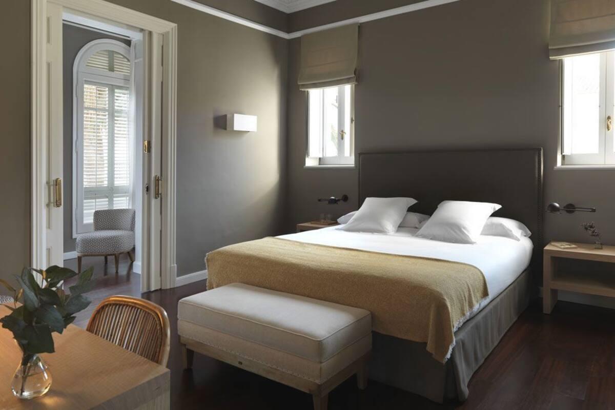 Une chambre à coucher avec un grand lit, une table de chevet, une chaise et une fenêtre.