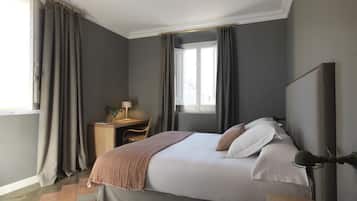 Een slaapkamer met een bed, bureau en raam.